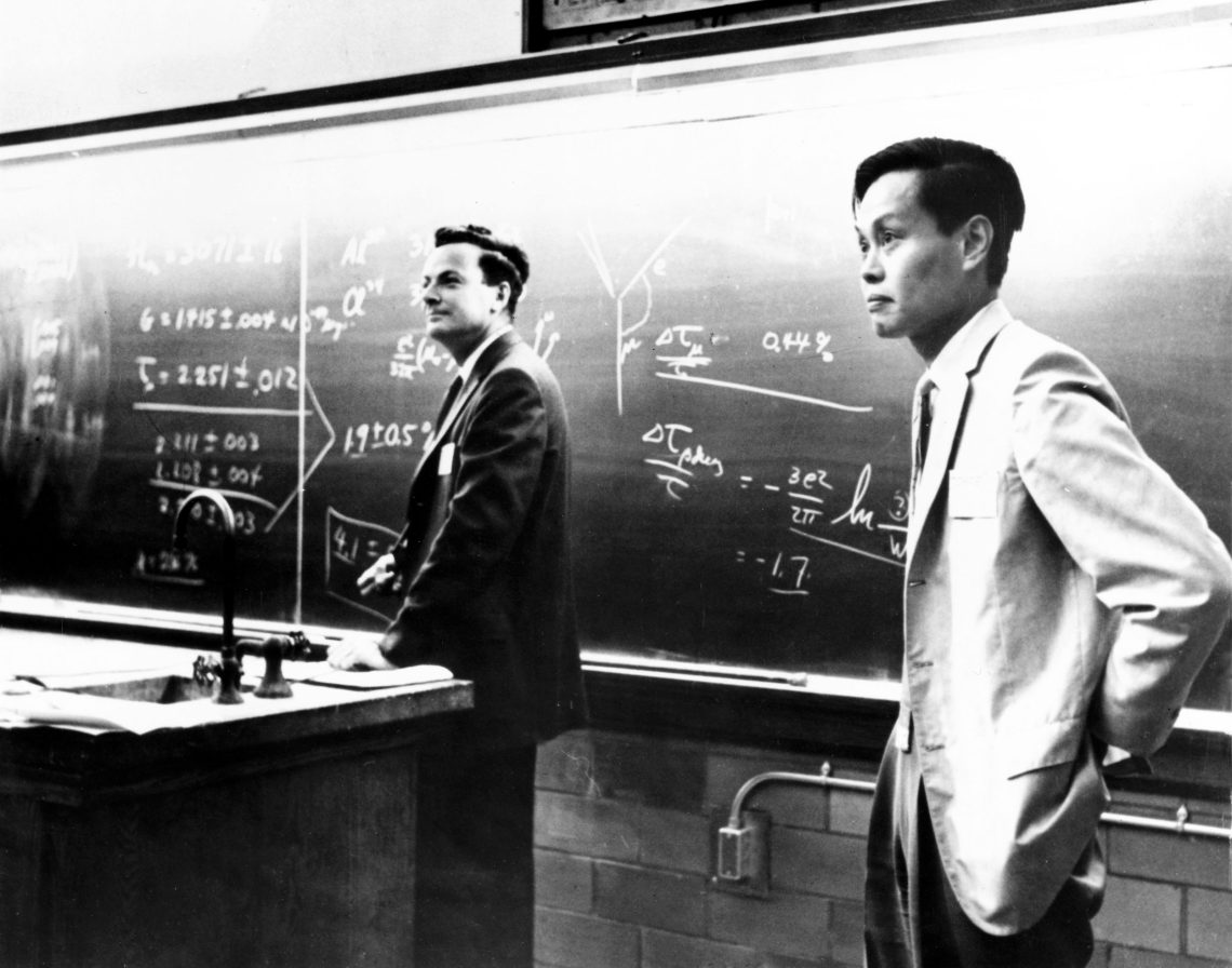 Richard Feynman und Yang Chen Ning stehen vor einer Tafel mit Formeln. Das Bild ist Teil eines Beitrags über Quanten.