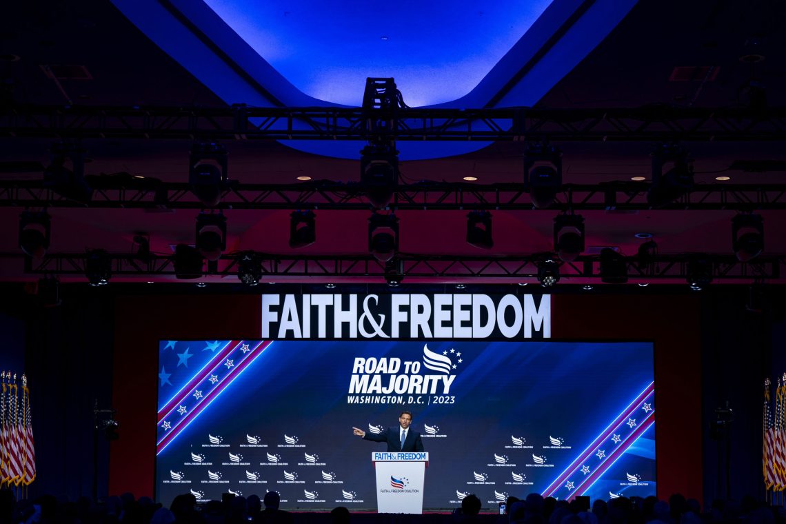 Foto von Ron de Santis an einem Rednerpult, im Zentrum des Bildes ist in großen Lettern die Aufschrift Faith and Freedom zu lesen. Das Bild illustriert einen Beitrag über Wehleidigkeit.