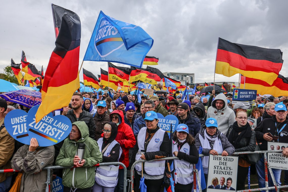 Auf einer Kundgebung gegen die Inflation stehen Anhänger der AfD gedrängt an einer Absperrung, viele tragen hellblaue Kappen, manche schwingen Fahnden der AfD bzw. Deutschlandfahnen.