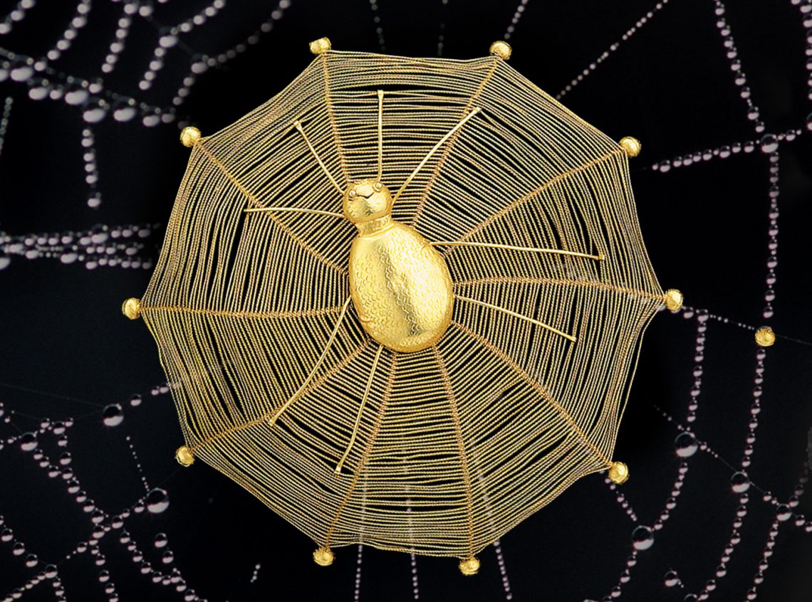Eine Kunstobjekt der afrikanischen Akan-Stämme aus Gold: die Spinne namens Anansi sitzt in Mitten eines filigranen Netzes aus Goldketten. Das Bild illustriert einen Beitrag über Afrikas kulturelles Erbe.