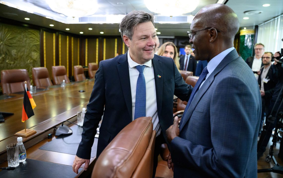 Der deutsche Wirtschaftsminister Robert Habeck und der namibische Wirtschaftsminister Tom Alweendo stehen in einem Besprechungsraum und reden miteinander.