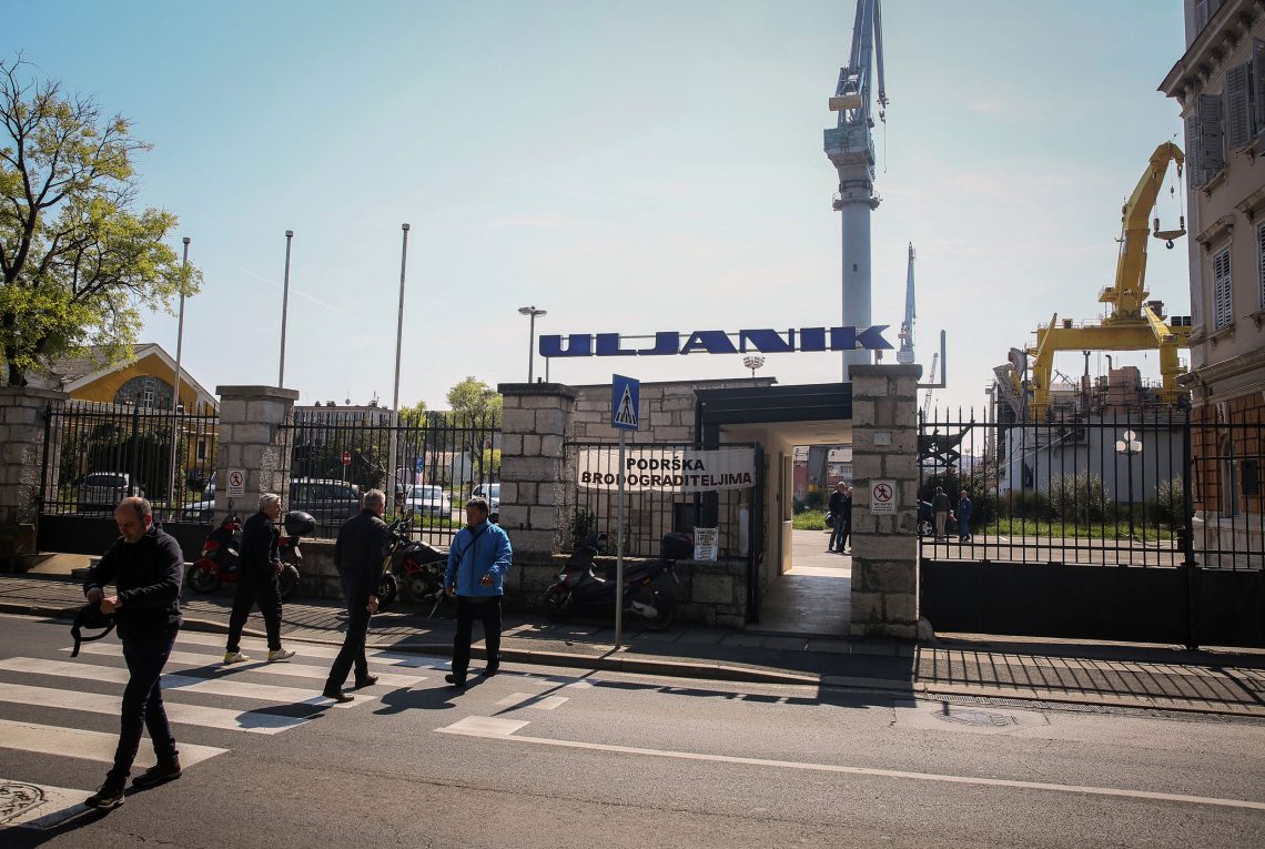 Männer verlassen ein Fabriksgelände auf dessen Tor der Schriftzug Uljanik zu lesen ist. Das Bild ist Teil eines zusammenfassenden Dossiers mit dem Titel Kann Europa sich selbst versorgen? 