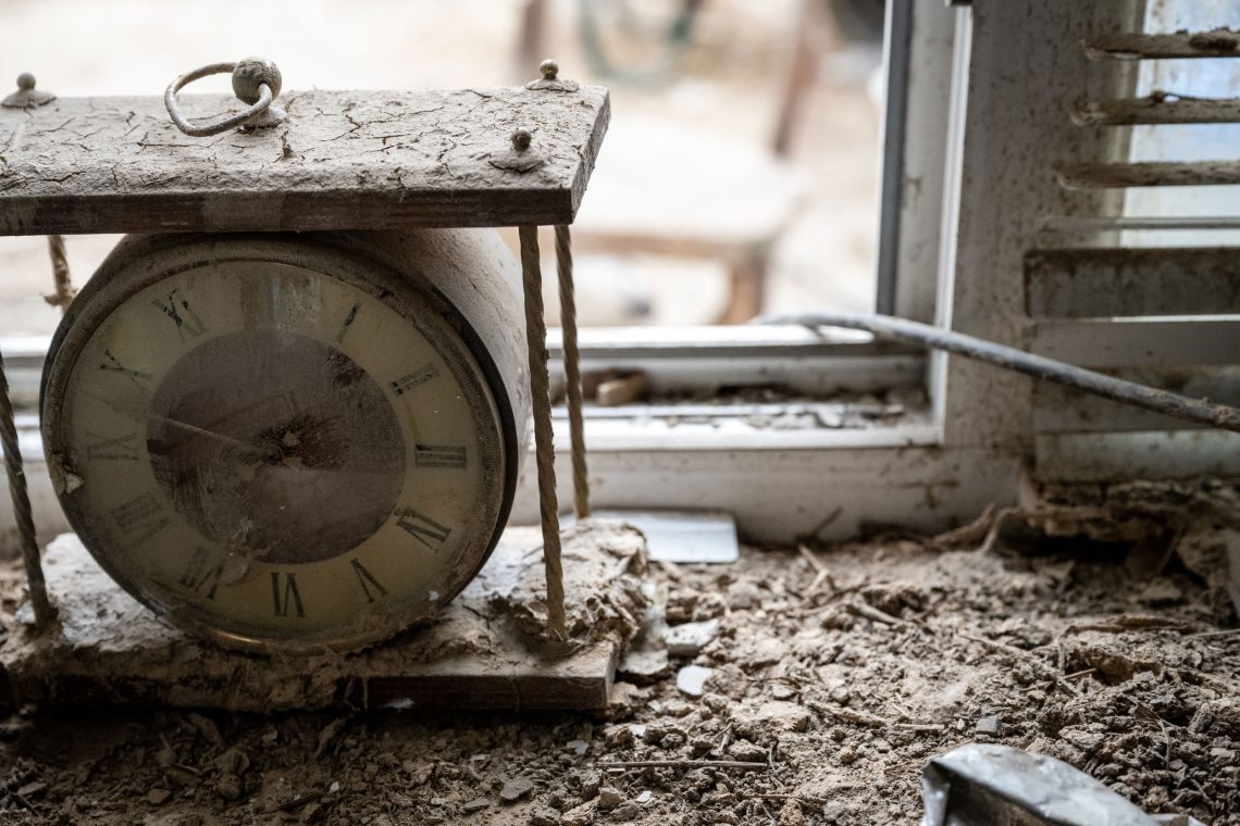 Foto eines mit Schlamm bedeckten Fensterbretts mit einer Uhr. Das Foto stammt aus der Gegend von Kherson nach der Zerstörung des Staudamms.