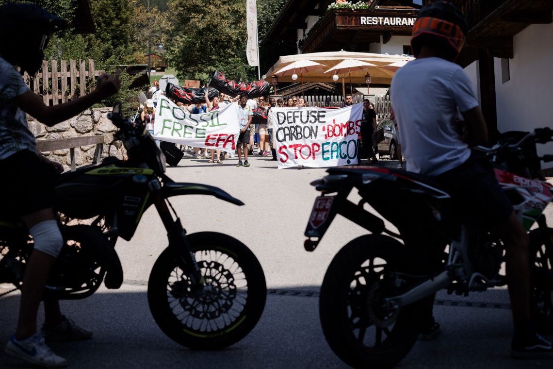 Foto von Motocross-Fahrern die eine Demonstration gegen eine Pipeline in Uganda und für ein nichtfossiles Foum Alpbach demonstrieren. Das Fot entstand während des Forum Alpbach in dem Tiroler Ort. Das Bild illustriert einen Beitrag über Klimapolitik und Verbote, es ist ein Interview mit Gernot Wagner.