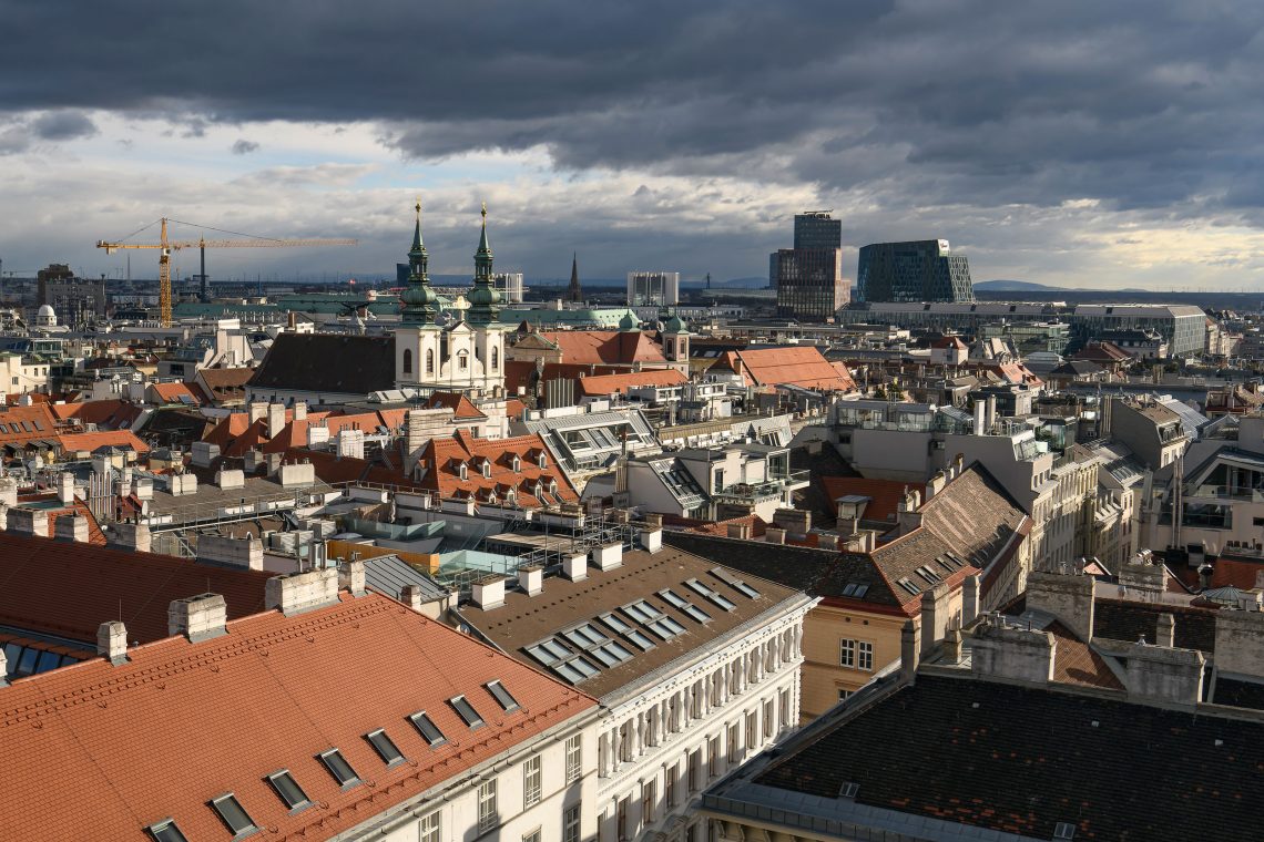 Dunkle Wolken ziehen in dieser Luftaufnahme über Wien. Im Bild die Rochuskriche und Wien Mitte mit Mall und Landgericht zu sehen ist. Das Bild illustriert einen Beitrag über Wohnungsmarkt und Zinsdeckel.