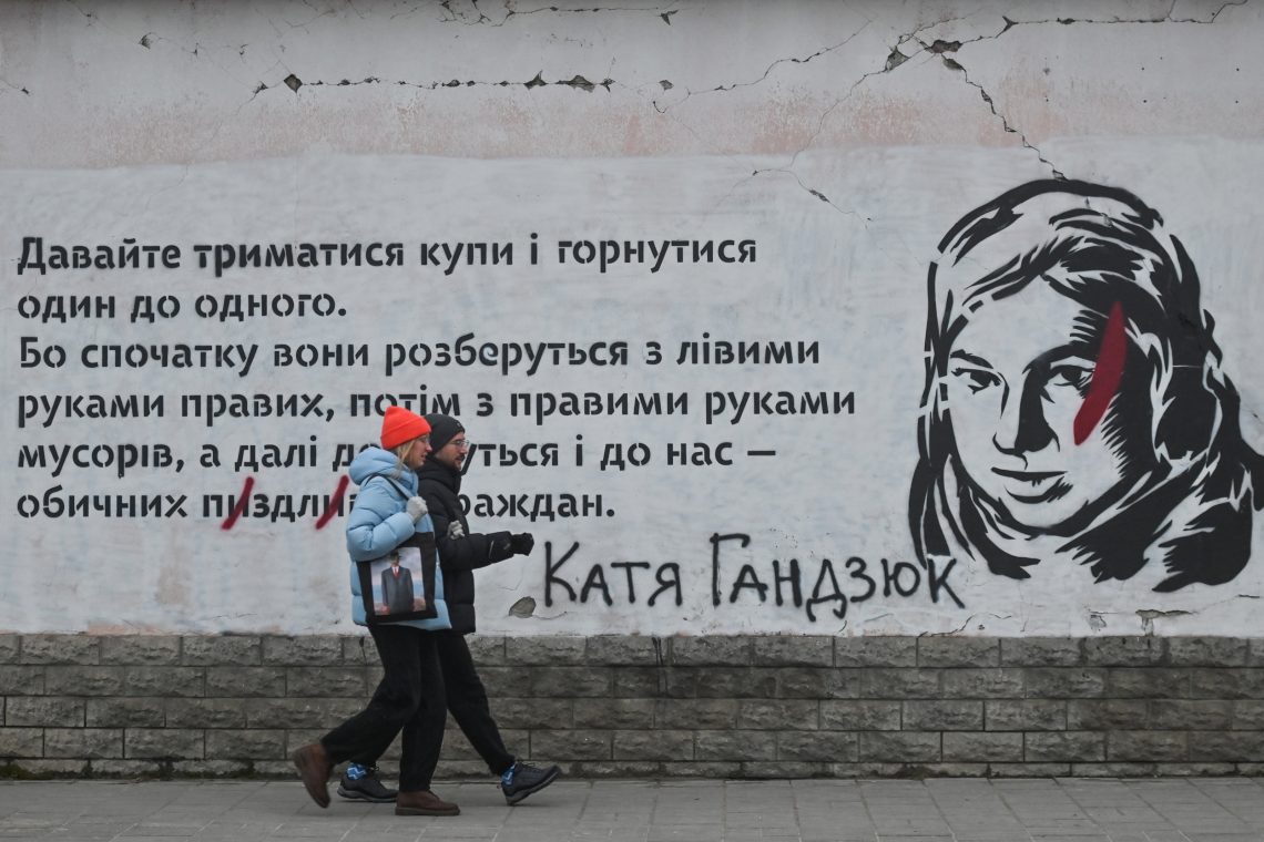 Zwei Ukrainer gehen an einem Wandgemälde in Gedenken von Kateryna Handziuk in Lemberg vorbei. Handziuk war eine ukrainische Aktivistin, die Korruption in ihrer Heimatstadt Cherson aufdeckte. Sie wurde 2018 mit Schwefelsäure angegriffen und starb.