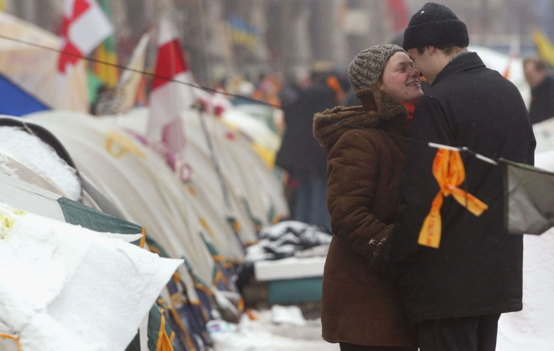 Ein Paar steht im Schnee vor einer Reihe von Zelten und lächelt sich an. Das Bild stammt von 2004 und zeigt die Proteste gegen den Wahlbetrug bei den Parlamentswahlen.