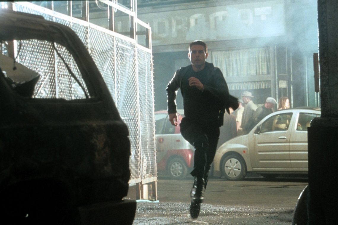 Filmstill aus dem Film Minority Report. Tom Cruise rennt in Richtung Kamera, im Hintergrund eine Straßenszene bei Nacht. Das Bild illustriert einen Beitrag, in dem es unter anderem um die Möglichkeit geht, Gedanken zu lesen.
