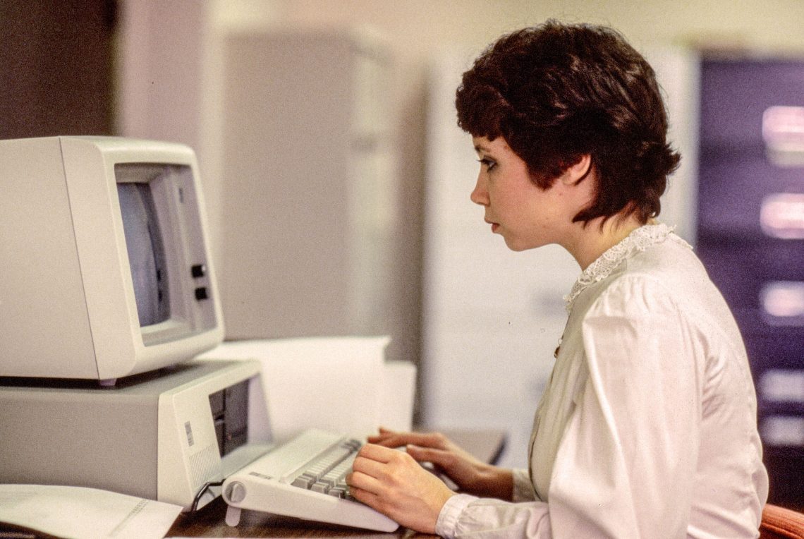 Eine Frau sitzt vor einem Computer. Das Bild ist Teil eines Beitrags über einen Mann, Neill Harbisson, der sich selbst als Cyborg sieht. Das Bild stammt von 1981 und soll zeigen, dass Computer und Mensch noch getrennte Welten waren, sich aber geistig annähern.