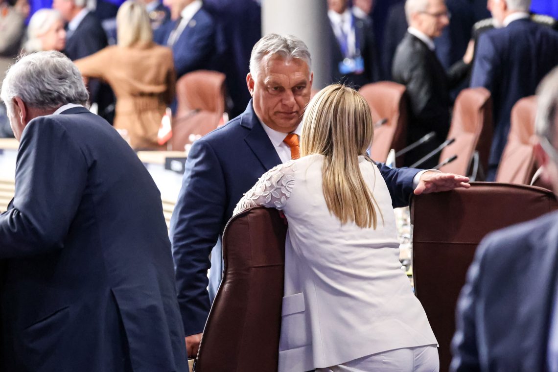 Viktor Orban und Georgia Meloni sprechen miteinander bei einer Pause einer Konferenz. Meloni hat die Arme auf die Sessellehne gestützt. Das Bild illustriert ein Interview über Populismus in Europa und die Herausforderungen der Europäischen Union.