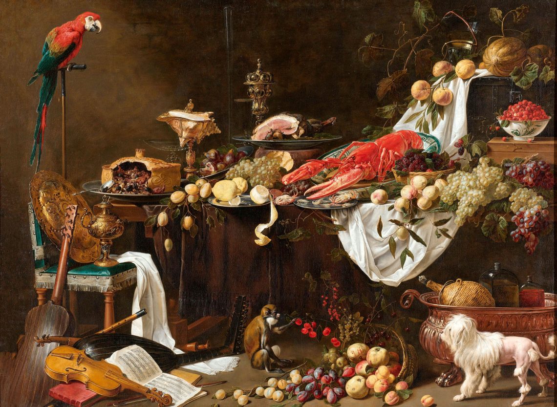 Adrian van Utrecht, Stilleven 1644. Das barocke Bild zeigt von teuren Speisen überquellende Tische mit einem großen Hummer, Zitronen und Orangen, Wein, einem Schinken. Ein Papagei blickt auf die Speisen, die auf den Tischen liegen. Auf dem Boden sitzt ein Kapuziner-Affe und ist rote Früchte. Ein kleiner weißer Hund sieht ihm zu. Eine Gitarr, eine Harfe, eine Viline und Notenblätter liegen am Boden. Das Bild ist Teil eines Beitrags, wie mit Essen Politik gemacht wird, da es darstellt, dass Essen und möglichst exklusive Speisen ein Symbol für Wohlstand und Opulenz waren.