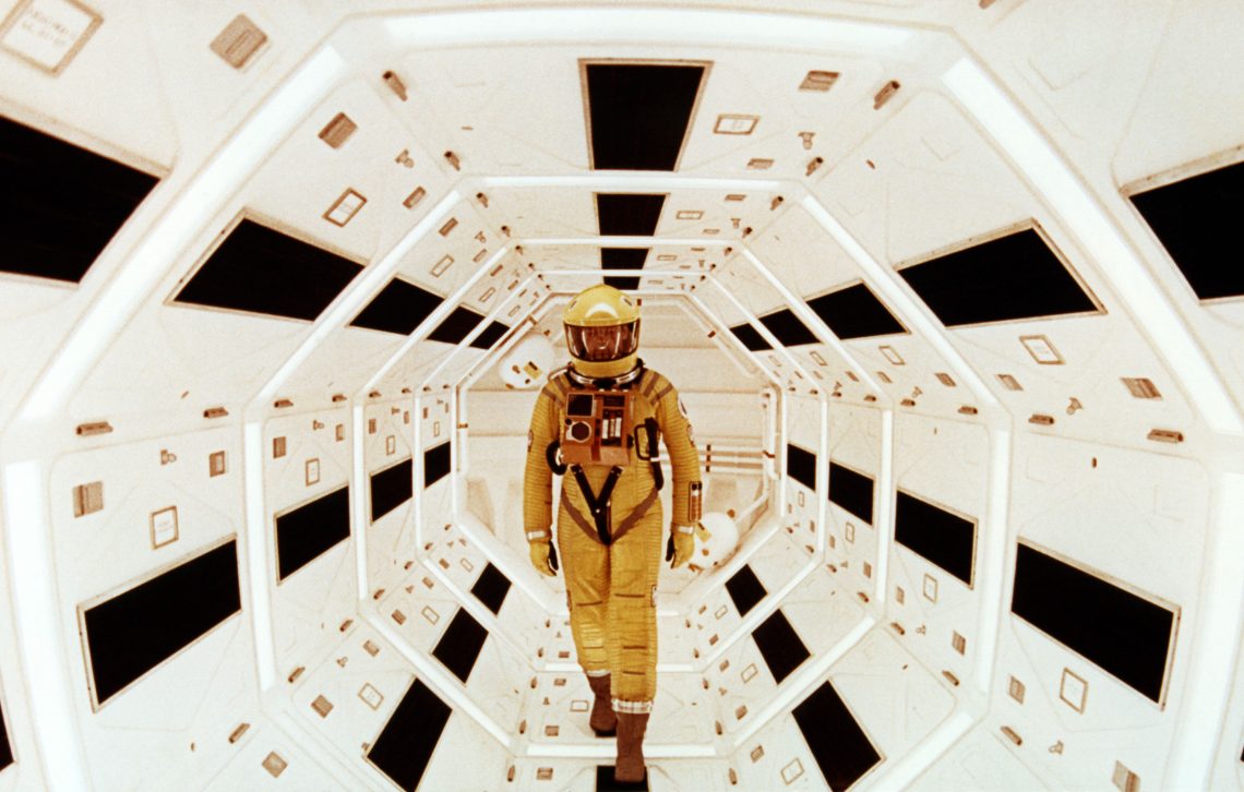 Szne aus dem Film von Stanley Kubrick 2001: A Space Oddyssey (1969). Ein Mann in einem geleben Raumanzug geht durch eine weiße Röhre auf den Betrachter zu. Das Bild gehört zu einem Dossier über Transhumanismus.