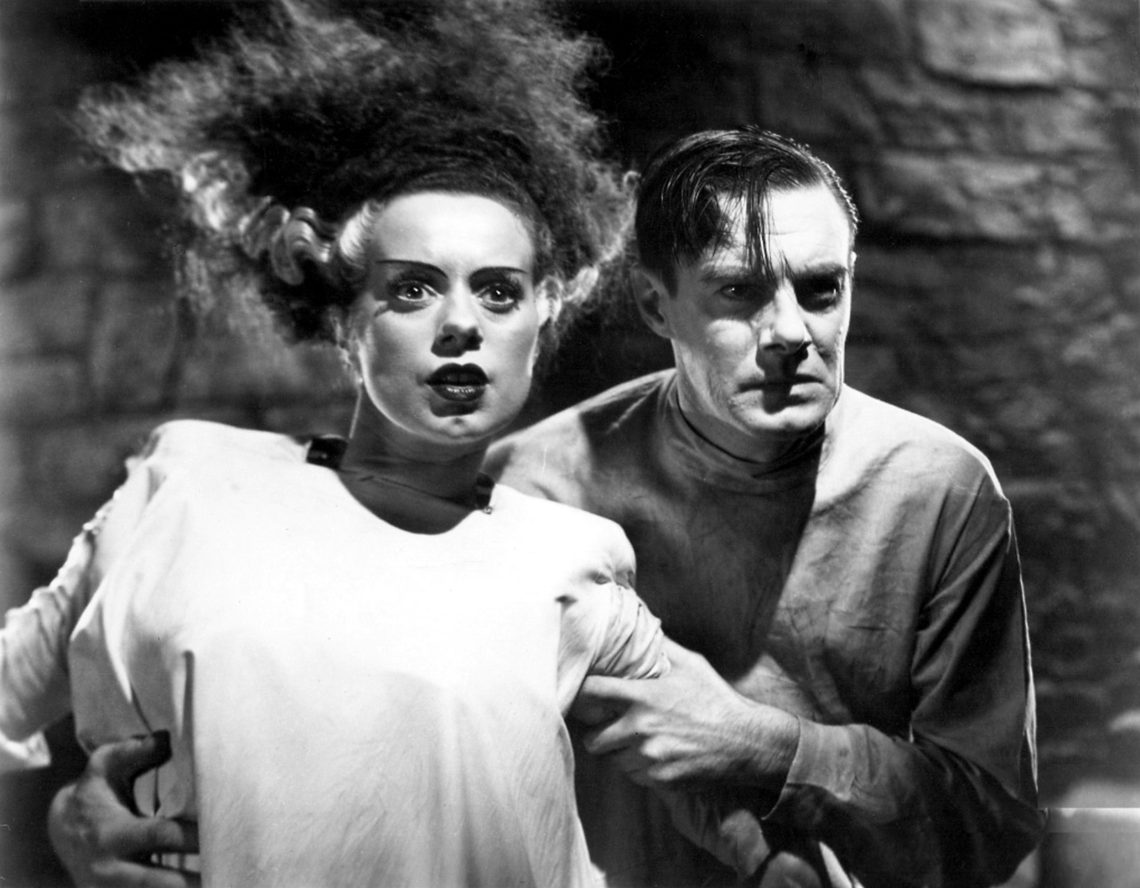 Elsa Lanchester und Colin Clive im Film Bride of Frankenstein. Lancast blickt entsetzt mit zu Berge stehenden Haaren in die Kamera, während Clive sie an den Armen zurückhält. Das Bild illustrert einen Beitrag über die Frage, was transhuman bedeutet.