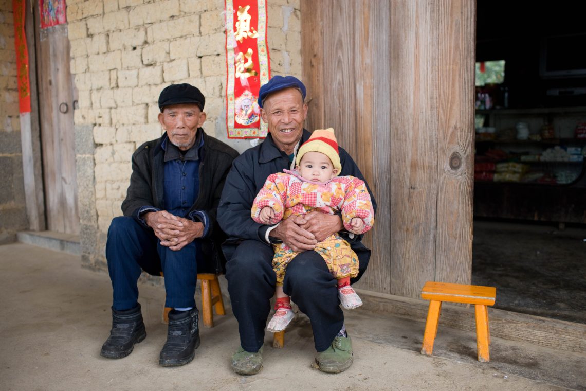 Zwei ältere Männer mit einem Baby in Fuli, einer malerischen historischen Stadt in der Provinz Guangxi, Südchina.