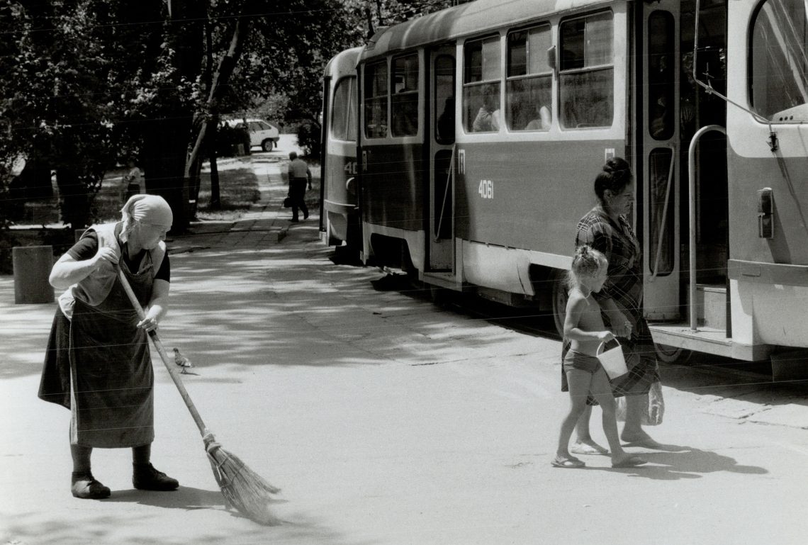 Schwarz-weiß Foto einer Straßenszene in Odessa mit Straßenbahn. Eine Frau kehrt die Straße, während eine Frau mit einem Kind an der Hand, das einen Sandeimer trägt die Straße entlang geht. Das Bild illustriert einen Beitrag über die verbreitete Annahme, dass die Ukraine russisch sei und keine eigenständige Nation.
