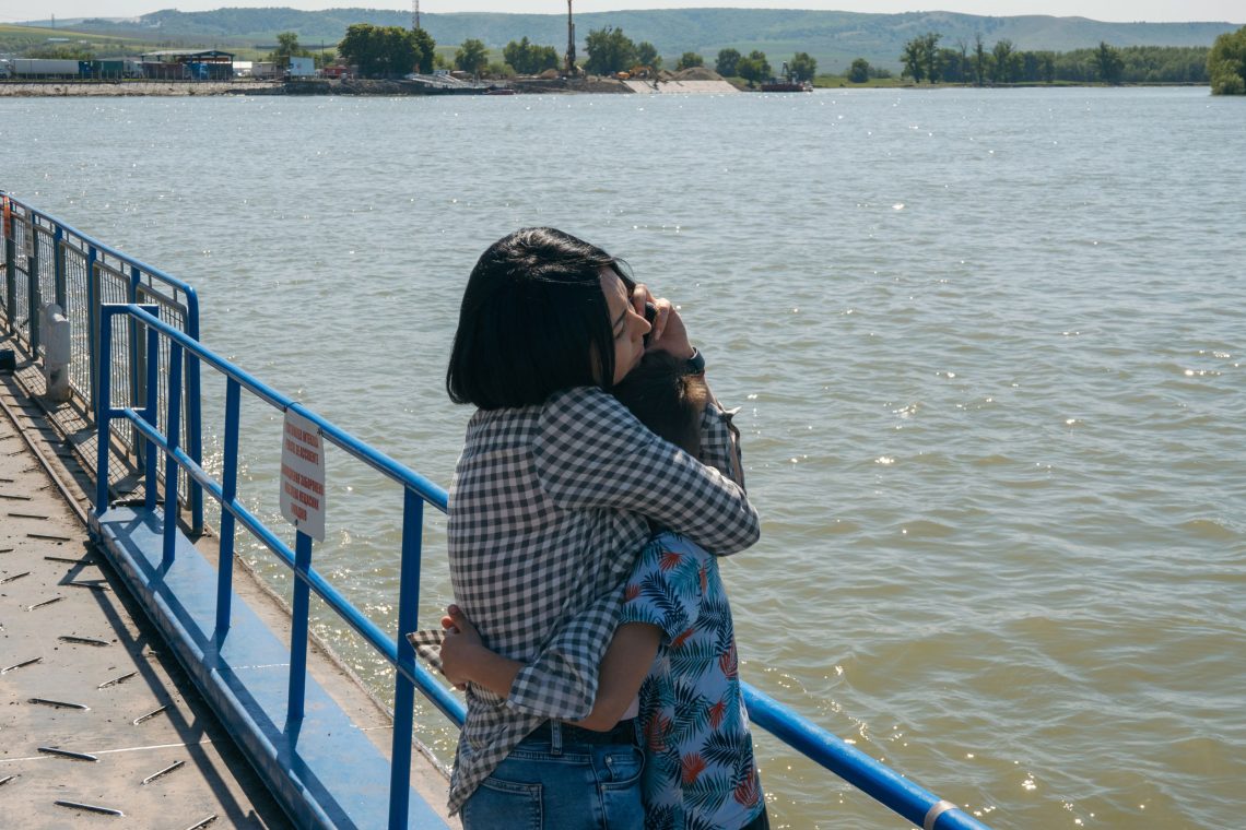 Eine Frau in einem karierten Hemd umarmt ein Kind. Die beiden stehen an der Reling einer Fähre. Das Bild ist Teil eine Beitrags über die Ukraine, die oft als russisch angesehen wird, obwohl sie es nicht ist.