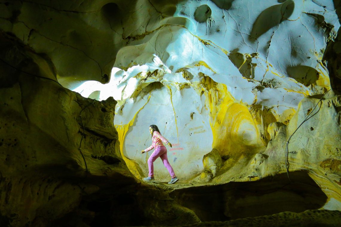 Eine Jugendliche geht durch die Karain-Höhle in der Nähe von Antalya in der Türkei. Sie geht genau in einem Lichtkegel, der durch den Eingang der Höhle zu scheinen scheint auf den sie zuschreitet. Das Bild illustriert einen Beitrag über Evolution, RNA und Alterung beim Menschen.