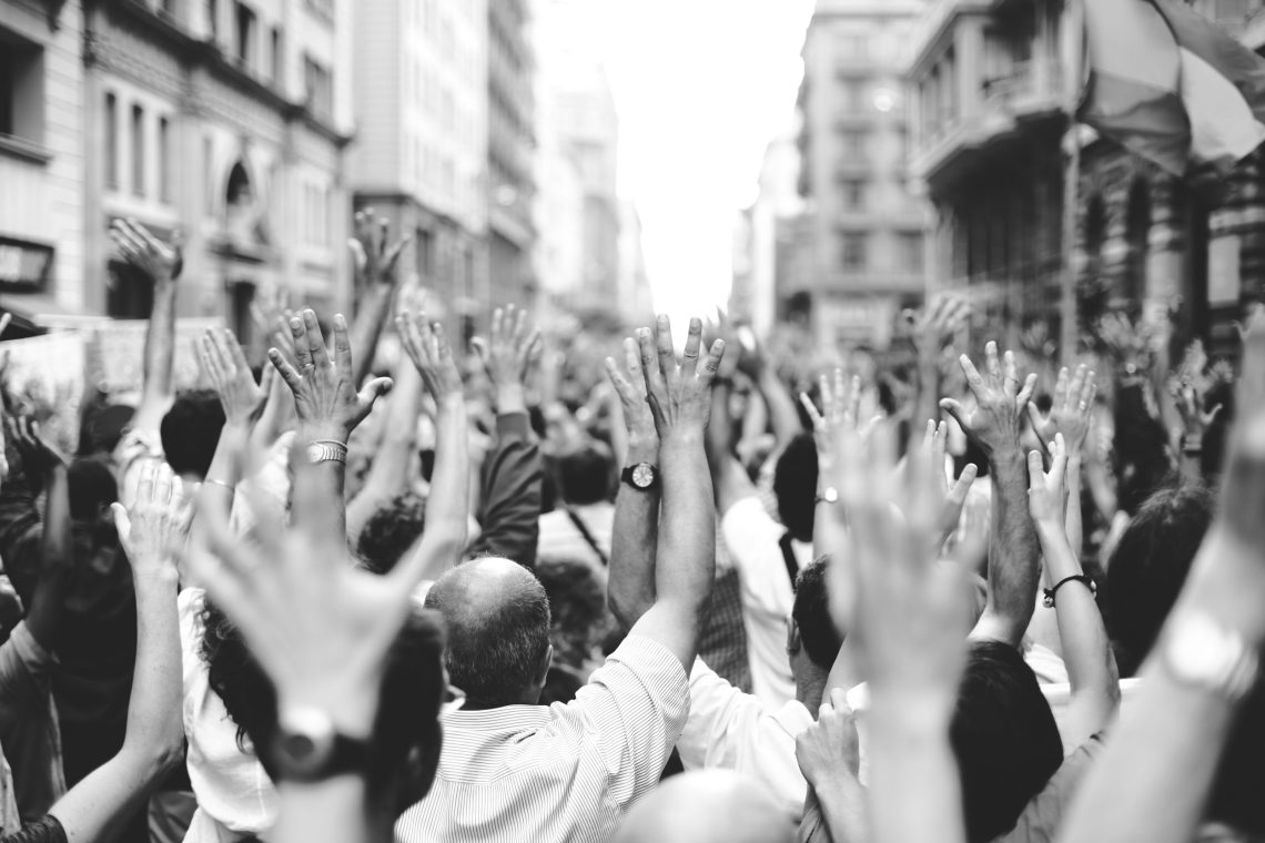 Menschen mit erhobenen Händen bei einer Demonstration. Das Bild illustriert einen Kommentar zum Thema Integration und die Grenzen der Toleranz.