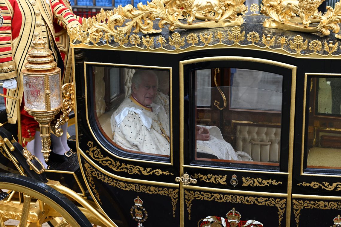 King Charles blickt aus dem Fenster der prächtigen Kutsche, in der er zur Krönungszeremonie gefahren wird.