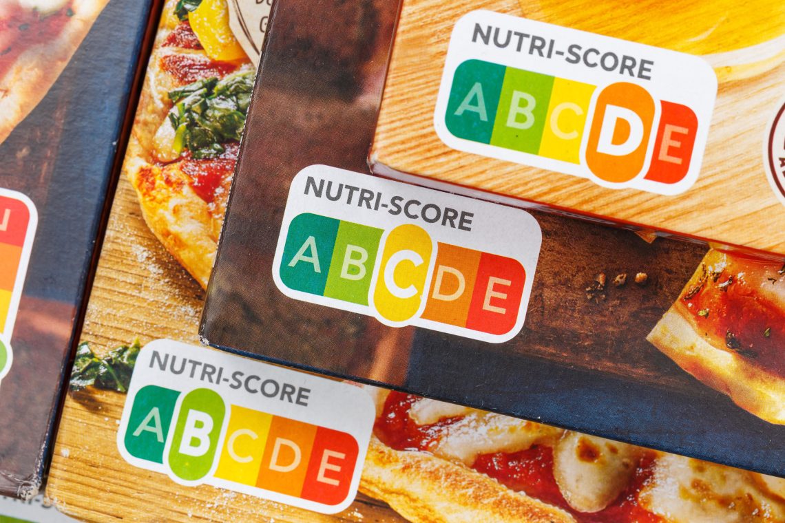 Nutri-Score auf drei gestapelten Pizza-Verpackungen.