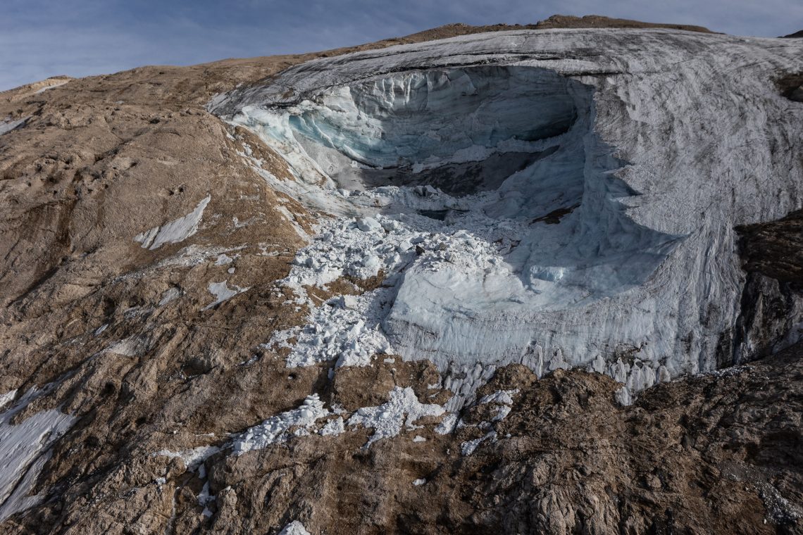 Drohnenaufnahme des Kraters, der durch den Gletscherbruch am Marmolata-Gletscher in Italien entstand. Der Gletscher war nur noch ein Fragment. Neben dem Krater aus schmutizigem Eis ist vor allem Fels zu sehen.