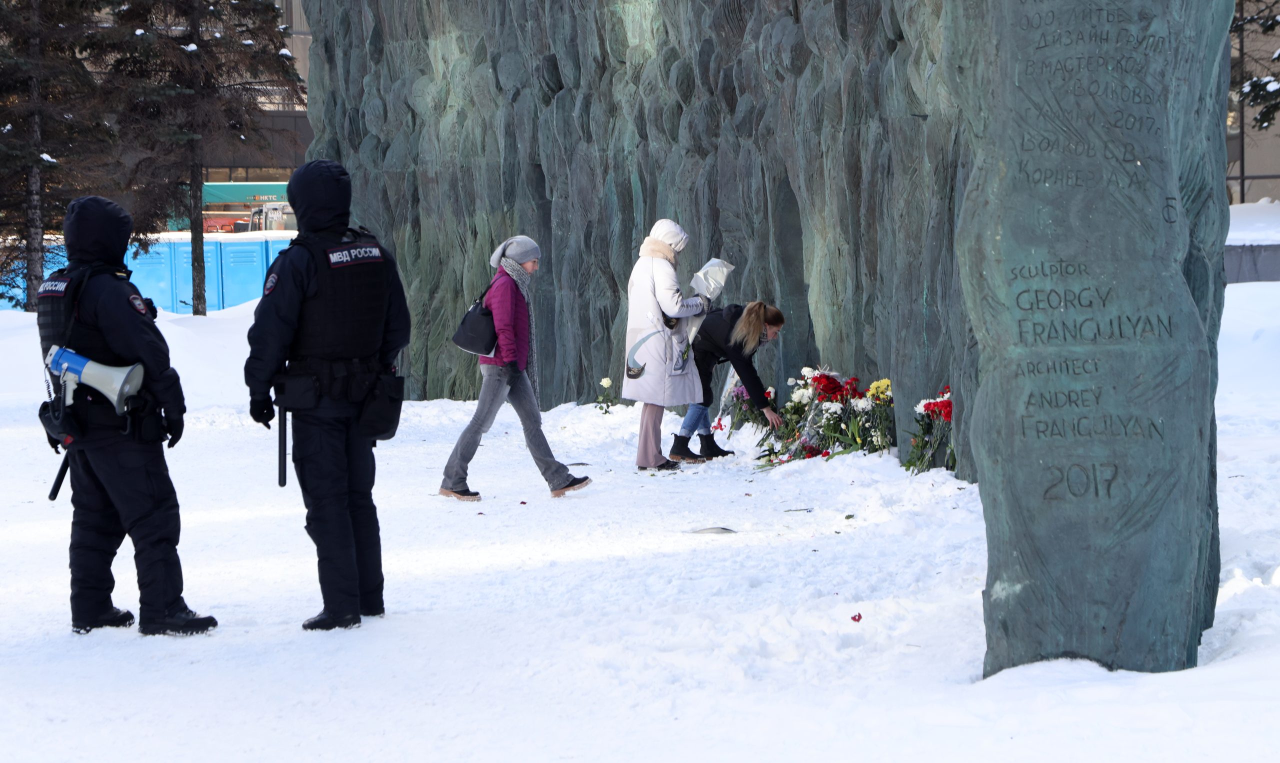 Russische Polizisten beobachten, Menschen, die Blumen an einem Denkmal zu Ehren der Opfer der sowjetischen Unterdrückung niederlegen. Moskau, am 19. Februar 2024. Das Bild illustriert einen Artikel über Russland nach Alexej Nawalnys Tod.