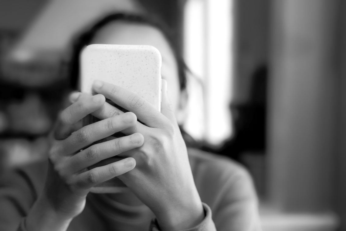Ein junges Mädchen schaut in ihr Smartphone. Das Bild illustriert einen Kommentar über die Angst der Generation Z vor alltäglichen Verrichtungen.