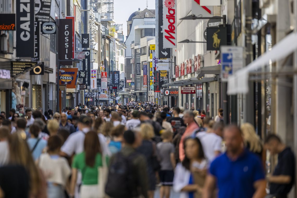 Menschen drängen sich auf der Hohen Straße, der Einkaufsstraße der Stadt Köln. Das Bild illustriert einen Artikel über Prognosen bei der Entwicklung der Weltbevölkerung in der Zukunft.