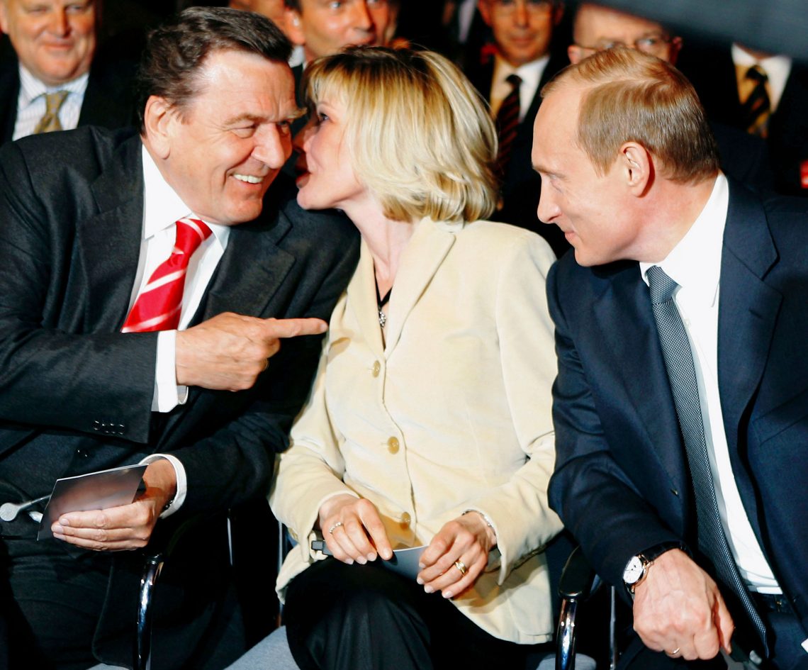 Gerhard Schröder Bundeskanzler von Deutshland deutet lachend mit dem Zeigefinger während er mit Wladimir Putin spricht. Doris Schröder-Köpf sagt Gerhard Schröder unterdessen etwas ins Ohr.