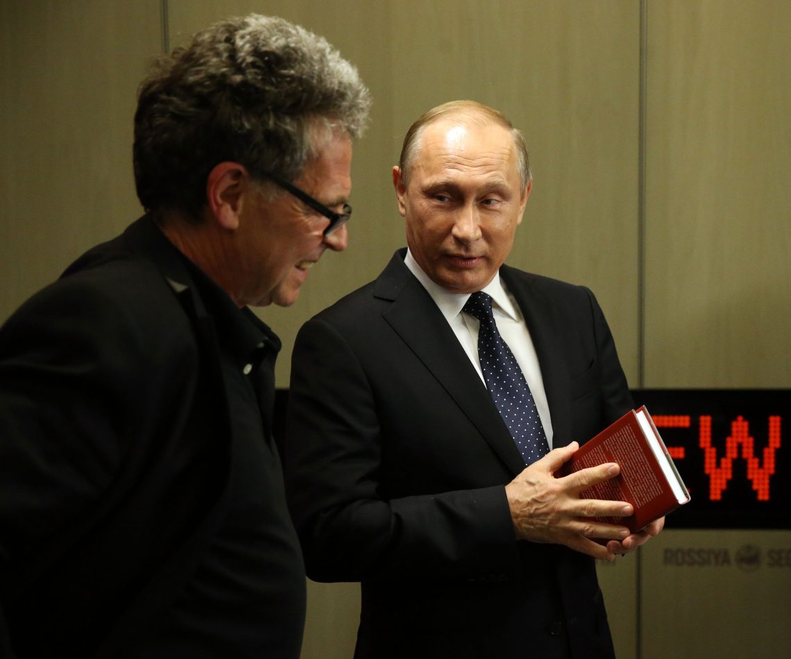 Hubert Seipel mit Wladimir Putin, der ein Buch in Händen hält. Beide lächeln.