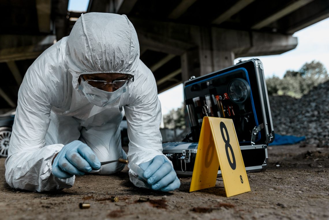 Ein Forensik-Ermittler sammelt Spuren an einem Tatort.