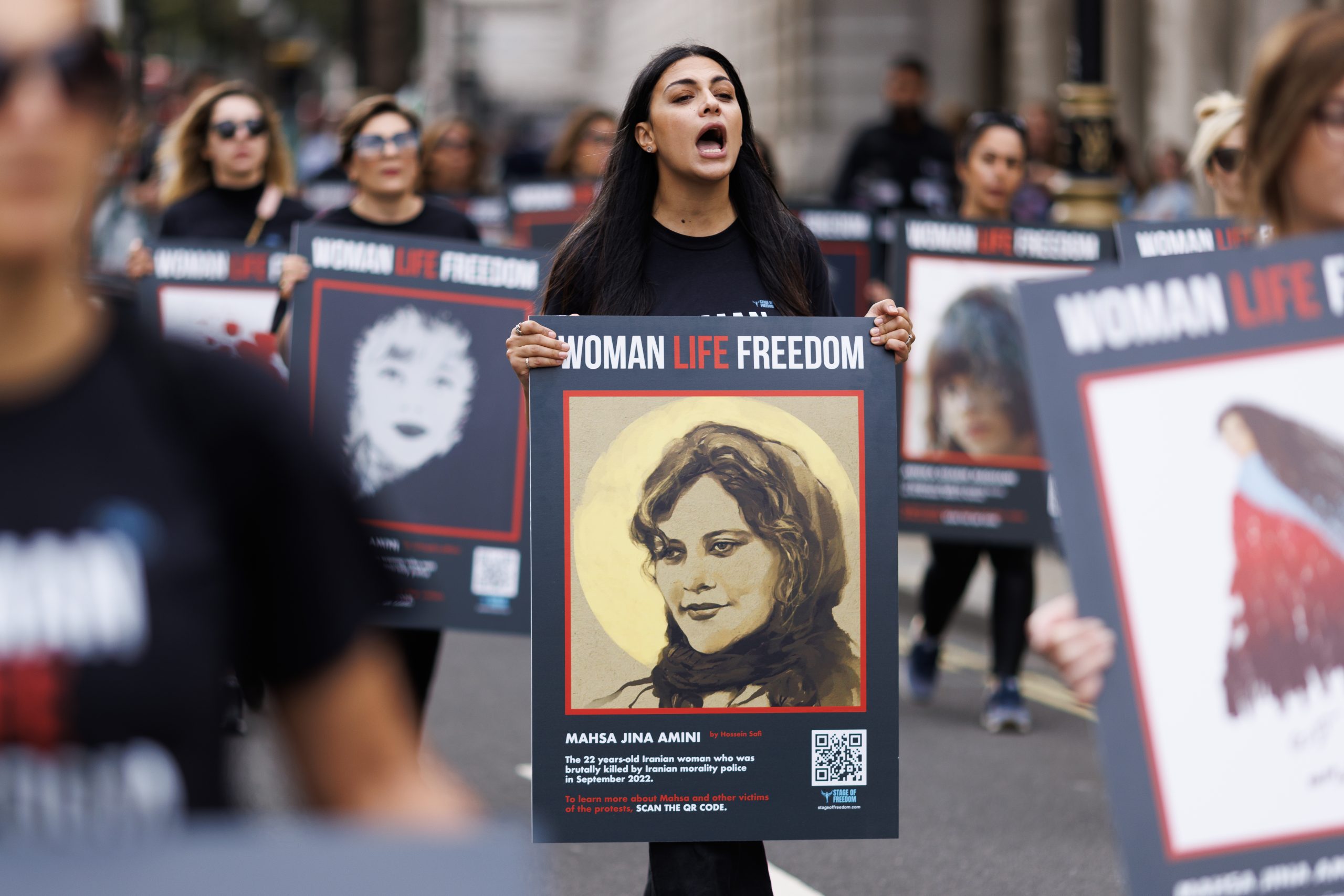 Eine Frau trägt ein Plakat mit der Aufschrift „Woman Life Freedom“ bei einer Demonstration im September 2023 in London. Das Bild illustriert einen Kommentar über das Tragen des Kopftuchs.