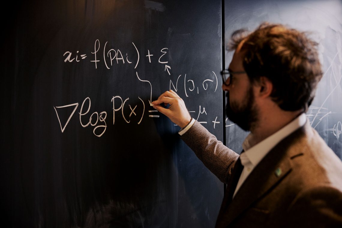 Ein Forscher steht vor einer Tafel und schreibt eine Formel