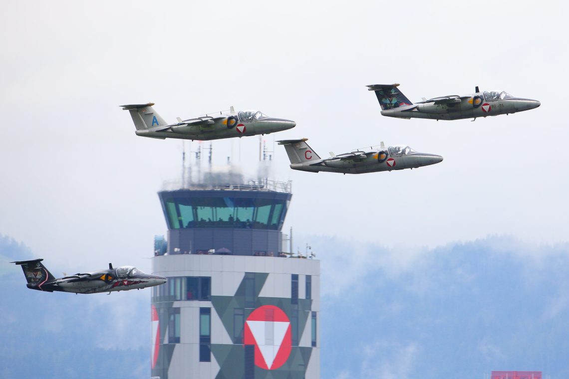 Vier Saab 105OE der österreichischen Luftwaffe fliegen bei der Airpower 2019 Flugshow in der Kaserne Fliegerhorst Hinterstoisser. Das Bild illustriert einen Kommentar über die Neutralität Österreichs.