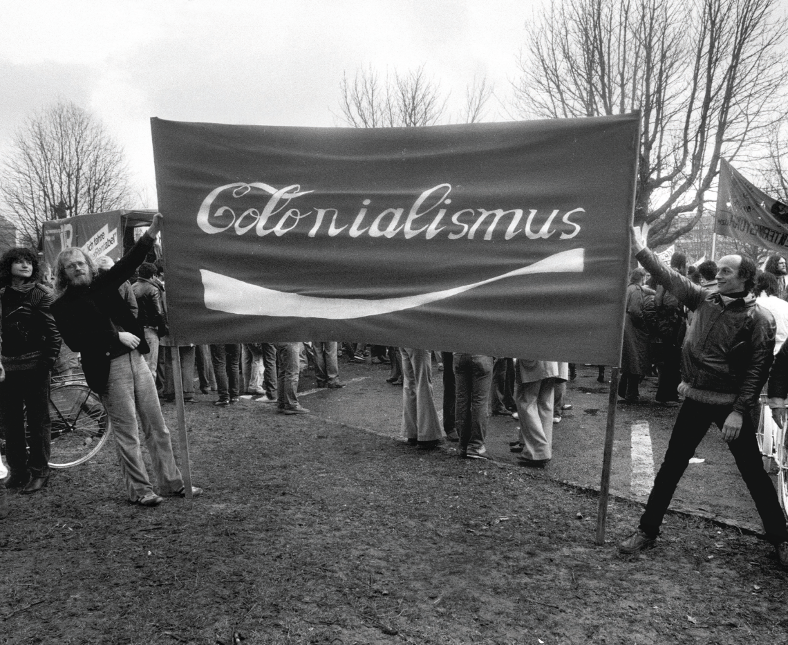Demonstranten halten 1982 in Frankfurt am Main ein Banner mit der Aufschrift „Colonialis- mus“ im typischen Schriftzug von Coca- Cola, um gegen die Einmischung der USA in Lateinamerika zu protestieren. Das Bild illustriert einen Beitrag über Antiamerikanismus.