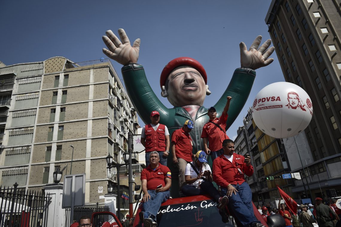 Anhänger der venezolanischen Regierung neben einer Ballonfigur des ehemaligen Präsidenten Hugo Chávez. Das Bild steht in einen Text über das Scheitern des Sozialismus.