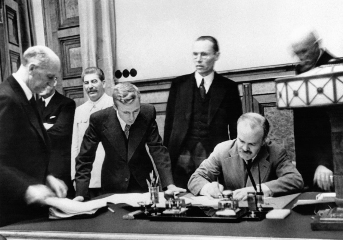 Der sowjetische Außenminister Wjatscheslaw Molotow bei der Unterzeichnung des Paktes in Moskau am 23. August 1939. Ganz links im Bild: Joachim von Ribbentrop, der außenpolitische Berater Hitlers. Im hellen Anzug Josef Stalin. Das Bild ist Teil eines Beitrags über den Hitler-Stalin-Pakt und seine Folgen.