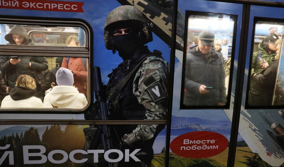 Titelbild zu einem Beitrag über Russlands Propaganda: Poster an Moskauer U-Bahn-Waggon: Russischer Soldat mit "V"-Symbol und Text "Wir werden zusammen siegen", 13. Dezember 2024.